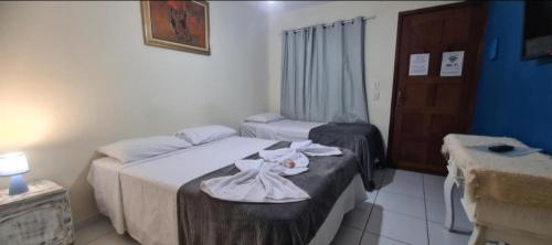 a hotel room with two beds and a table with dishes at Pousada Cantinho do Sagui Inn in Búzios