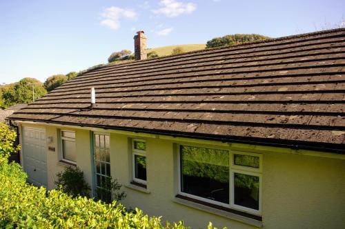 a yellow house with a shingled roof at Abbotscot, near Bantham, an eccelectic property with a lovely garden in Bantham