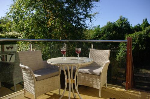 a table with two glasses of wine on a balcony at Abbotscot, near Bantham, an eccelectic property with a lovely garden in Bantham