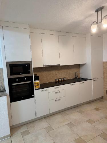 a kitchen with white cabinets and a black appliance at Dardania Hostel in Peje