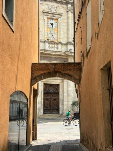 une personne faisant du vélo devant un bâtiment dans l'établissement Valmy Cosy - Appartement entier - Hypercentre, à LʼIsle-sur-la-Sorgue