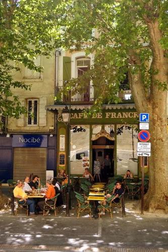 un groupe de personnes assises à des tables à l'extérieur d'un restaurant dans l'établissement Valmy Cosy - Appartement entier - Hypercentre, à LʼIsle-sur-la-Sorgue