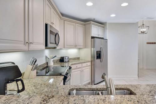 a kitchen with white cabinets and a stainless steel refrigerator at Salty Breeze in Saint Simons Island