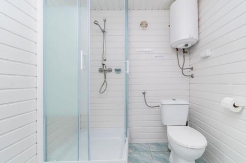 a white bathroom with a shower and a toilet at Neptun Ośrodek Wypoczynkowy in Jantar