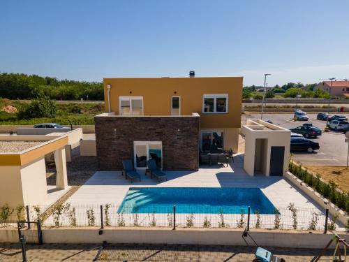 a villa with a swimming pool and a parking lot at Vacation House Privlaka in Privlaka