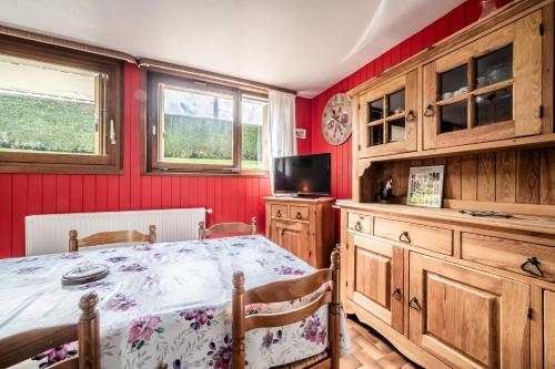a dining room with a table and a tv and red walls at Appartement en residence in Morzine