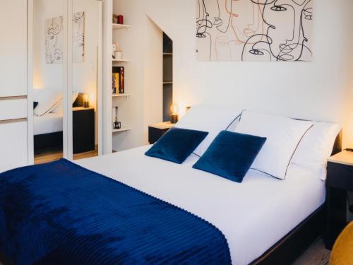 une chambre avec un grand lit blanc avec des oreillers bleus dans l'établissement 36 2 L'air marin Penthouse climatisé Netflix Stationnement gratuit Accès direct Autoroutes et plages, à Narbonne