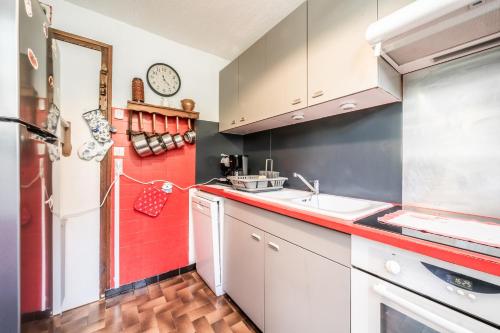 a kitchen with a sink and a red wall at Appartement en residence in Morzine