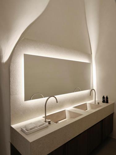 a bathroom with a sink with a large mirror at Andronis Luxury Suites in Oia