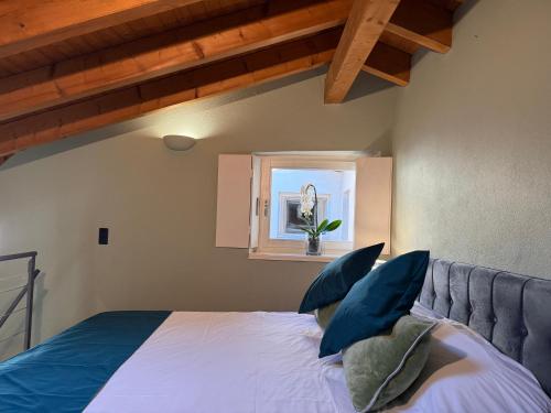 a bedroom with a bed with blue pillows and a window at Gritti Palace Morcote - Salvia - Loft by the lake with view of Morcote's church in Morcote