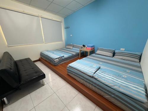 a room with two beds and a chair in it at 美菊民宿 停車方便 市中心 in Chaozhou