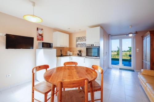 une cuisine et une salle à manger avec une table et des chaises en bois dans l'établissement Gite l'hermine, à Cast