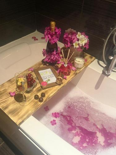 a bath tub with a tray with flowers and a sink at City Tales Residence in Braşov