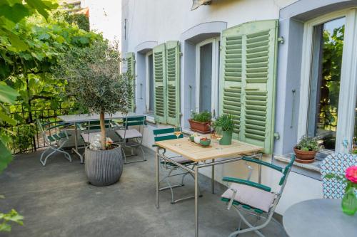 a patio with tables and chairs and shuttered windows at BnB Feuille de Vigne in Saint-Léonard