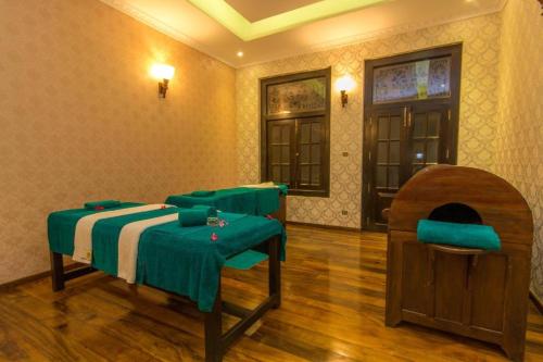 a room with a bed with green sheets and chairs at New Hotel Kabalana in Ahangama