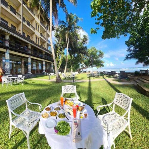 a table with food on it with chairs and a building at New Hotel Kabalana in Ahangama
