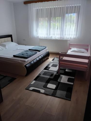 a bedroom with two beds and a bench and a rug at Apartman Aldina in Bihać