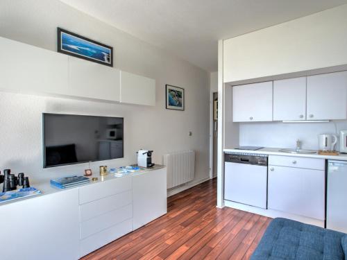 une cuisine avec des armoires blanches et une télévision à écran plat dans l'établissement Studio cosy avec accès direct à la plage - FR-1-474-111, à Arcachon