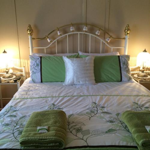 a bed with green and white sheets and pillows at Lillymay Cottage in Broken Hill