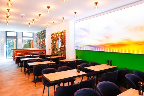 a restaurant with tables and chairs and a green wall at Sleephotels Cosmos in Hamburg