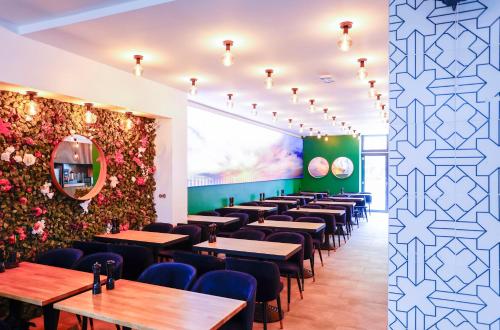 a restaurant with tables and chairs and a wall of flowers at Sleephotels Cosmos in Hamburg