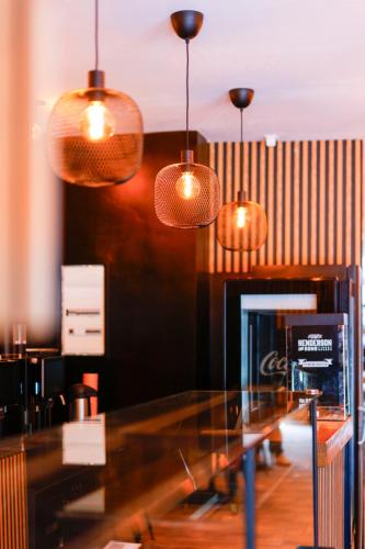 a glass counter in a restaurant with pendant lights at Sleephotels Cosmos in Hamburg