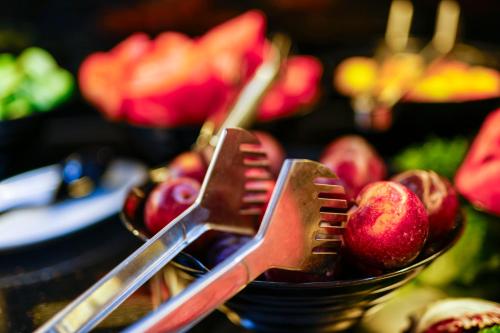 a basket of apples with two plastic utensils in it at Sleephotels Cosmos in Hamburg