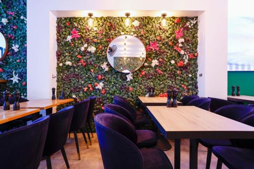 a wall of flowers in a restaurant with tables and chairs at Sleephotels Cosmos in Hamburg