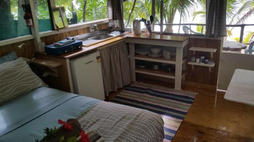 a kitchen with a sink and a bed in a room at Matriki Beach Huts in Arutanga
