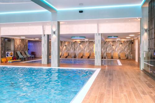 a swimming pool in a hotel lobby with chairs at Forest Park Resort & SPA in Świeradów-Zdrój