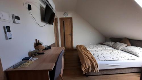 a bedroom with a bed and a desk with a television at Sarokhaz Panzio in Vecsés