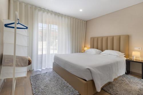 a bedroom with a large bed and a large window at Sidro House - Alojamento No Gerês in Geres
