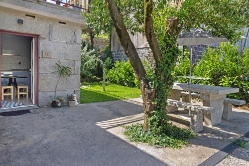 a patio with a table and a bench next to a building at Sidro House - Alojamento No Gerês in Geres