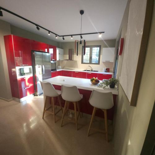 a kitchen with red cabinets and a white island with stools at Evia Palm Beach Villa in Politiká
