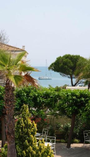 a palm tree with chairs and a boat in the water at Villa Miraé by Inwood Hotels - Cap d'Antibes in Antibes
