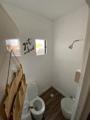 a white bathroom with a toilet and a window at Philipp's Beachfront Cabin - Calatagan in Calatagan