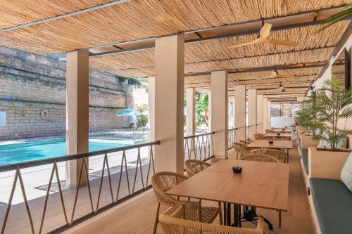 a restaurant with tables and chairs and a swimming pool at FLOR los Almendros Apartamentos in Paguera