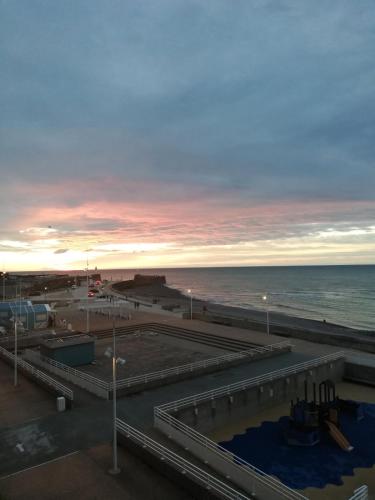 a view of the ocean and the beach at sunset at Le Grand Bleu in Saint-Valéry-en-Caux
