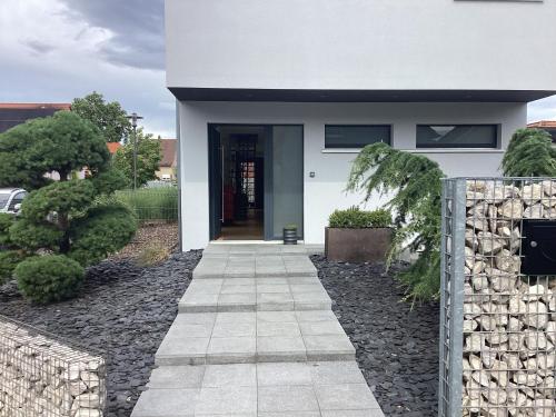 une maison blanche avec un mur de pierre et une passerelle dans l'établissement Maison d’architecte située sur la route des vins, à Châtenois