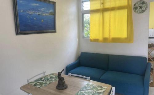 a living room with a blue couch and a table at Appartement Azalée in Fort-de-France