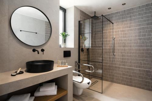 a bathroom with a shower and a sink and a mirror at Pnoes Luxury Suites in Paliouri