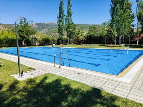 a large swimming pool with blue water in a park at Hotel La Casa Grande del Burgo in El Burgo