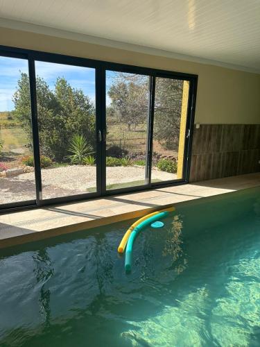 une piscine avec une frite de piscine devant une fenêtre dans l'établissement L'étoile du Matin avec Piscine Privative, à Margon