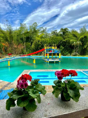 a pool with two flowers and a boat in the water at HOTEL Parque recreacional EL LAGO LIBANO in Líbano