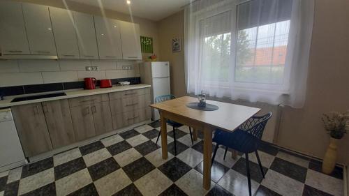 a kitchen with a table and chairs and a refrigerator at Négy Évszak Vendégház Nyúl in Nyúl