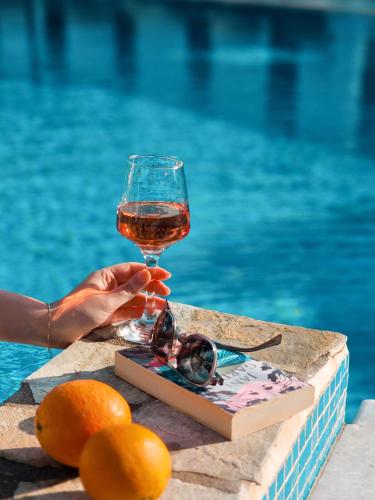 a person holding a glass of wine next to a pool at Hotel Benois in Galissas