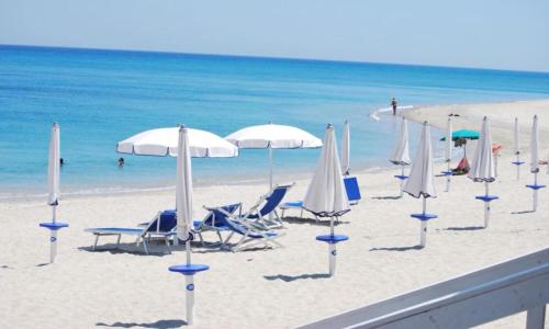 a beach with chairs and umbrellas and the ocean at Solea Village sul mare in San Sostene Marina