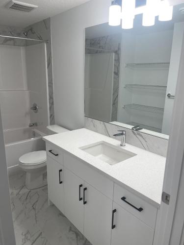 a bathroom with a sink and a toilet and a mirror at Westminister Manor in YYC