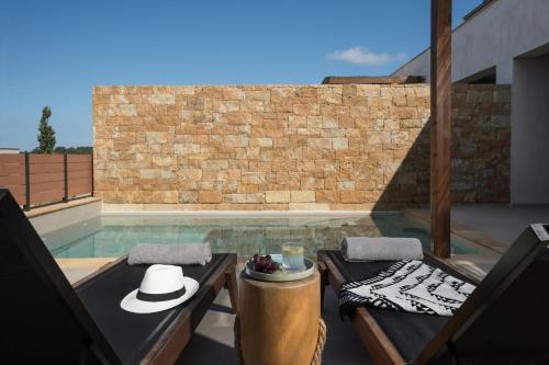 a patio with a table and two chairs and a pool at Pnoes Luxury Suites in Paliouri