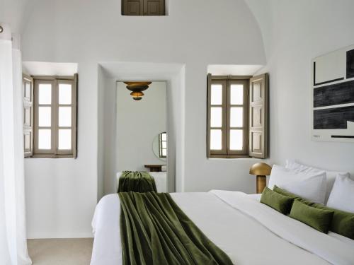 a bedroom with a white bed and two windows at Andronis Luxury Suites in Oia